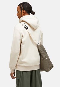 Beige sweatshirt med justerbar hætte, lange ærmer og ribbet kant. Olivengrøn crossover taske med tekstureret overflade og sort hardwarerem.