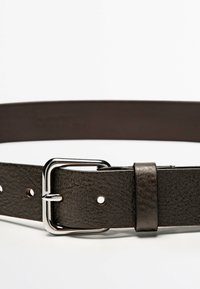 Mörkbrunt läderbälte med texturerad finish, som har en metallisk silver spänne och spärr. Fem justeringshål syns längs remmen.