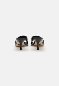 Black patent leather mules with a pointed toe and slim stiletto heel. The design features open sides and a smooth texture.