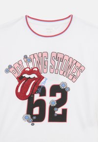 Balts īsajām piedurknēm T-krekls ar sarkanu mirdzošu mēles logotipu, "ROLLING STONES 62" treknā melnā krāsā un zilām ziedu akcentiem.