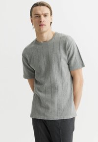 Szara, krótkorękawowa koszulka z dzianiny z poziomymi paskami i okrągłym dekoltem. Miękka tekstura, luźny krój i standardowy krój dołu.