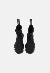 Botines negros de tobillo hechos de un material textil elástico con un diseño elegante y sin costuras. Presenta una puntera redonda y una suela de goma con una etiqueta de tirado con el logo.
