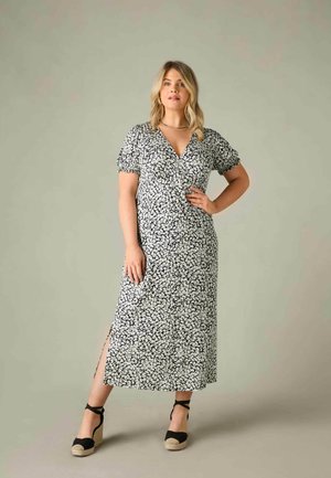 Sort og hvid blomsterkjole med korte puffærmer, dyb V-hals, sideslids og et flydende design. Parret med sorte espadrille wedges.