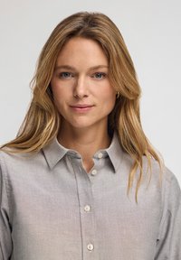 Ljusgrå button-up skjorta med krage, som har en mjuk textur, subtila sömnadsdetaljer och fyra framknappar.