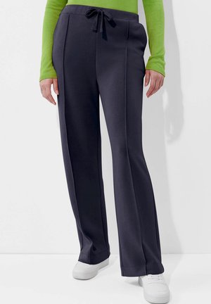 Navy wijde broek in zachte stof met een trekkoord in de taille, voorzien van zijzakken en een gladde textuur, gecombineerd met witte sneakers.