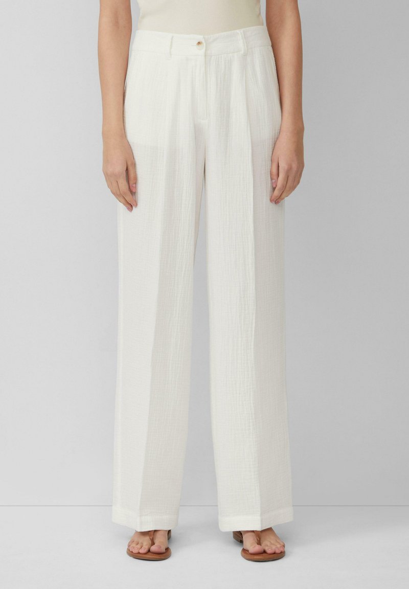 Pantalons blancs à jambes larges en tissu texturé. Comprend une fermeture à boutons sur le devant, des plis et un ourlet droit qui tombe aux chevilles.