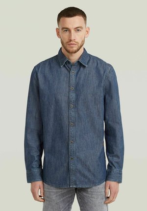 Dark blue denim shirt with button closure, long sleeves, and a classic collar. Features a textured fabric and slightly curved hem.