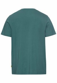 Teal bomulds T-shirt med klassisk rund hals, korte ærmer og lige kant. Har et lille mærke ved venstre side søm.