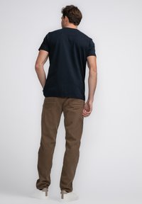 Navy katoenen T-shirt, korte mouwen, ronde halslijn, gecombineerd met bruine corduroy broek, met een rechte snit en achterzakken. Witte sneakers.