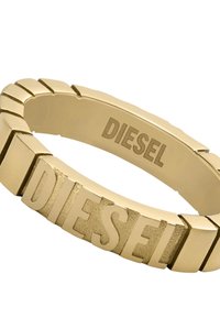 Goldfarbener Ring mit geometrischem Design, der erhabene "DIESEL"-Buchstaben zeigt. Strukturierte und glatte Oberflächen sorgen für einen visuellen Kontrast.