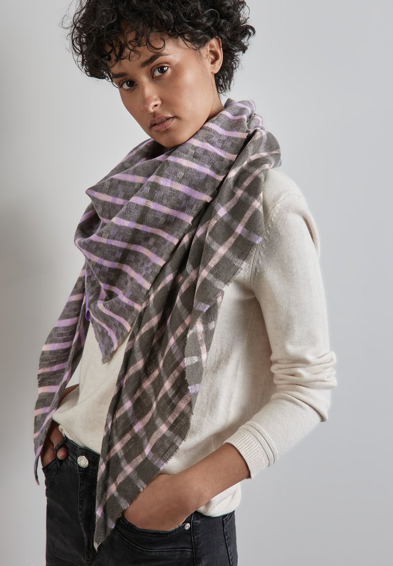 Écharpe à carreaux gris et lavande en tissu léger, tombant lâchement sur un pull clair. Les bords effilochés et la texture douce sont visibles.