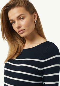 Marineblauer gestreifter Pullover mit weißen horizontalen Streifen, Rundhalsausschnitt und weichem Stricktextur, getragen von einer Person mit langen Haaren.