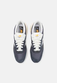 Tenisky New Balance v námořnické modré a bílé barvě z materiálů síťoviny a semiše. Vybaveny bílými tkaničkami a texturovanou krémovou podrážkou.