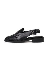 Zapatos slingback de cuero negro con puntera redonda, detalle plisado en la parte frontal y un bajo tacón cuadrado. Acento de herrajes en tono plateado.