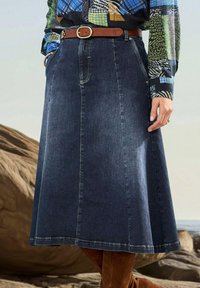 Jupe en denim bleu foncé avec un design évasé en A, dotée de poches avant, de coutures piquées et d'une ceinture en cuir marron avec une boucle en métal.