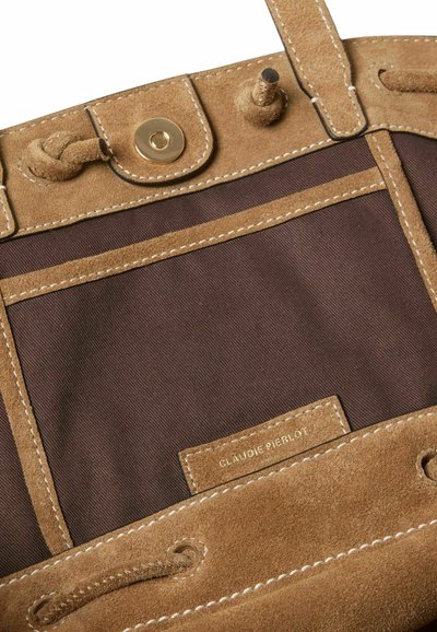 Interior de bolso de cuero de ante en tonos marrones con forro de tela oscura, que cuenta con un bolsillo y herrajes dorados. Los acentos cosidos mejoran la durabilidad y el diseño.