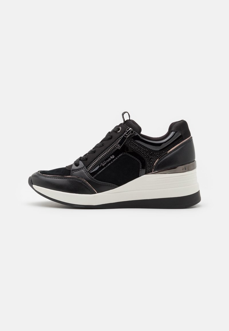 Pantofii sport negri sunt fabricați dintr-un amestec de piele lacată netedă, suede și plasă. Sunt concepuți cu o închidere cu fermoar și o talpă înclinată.