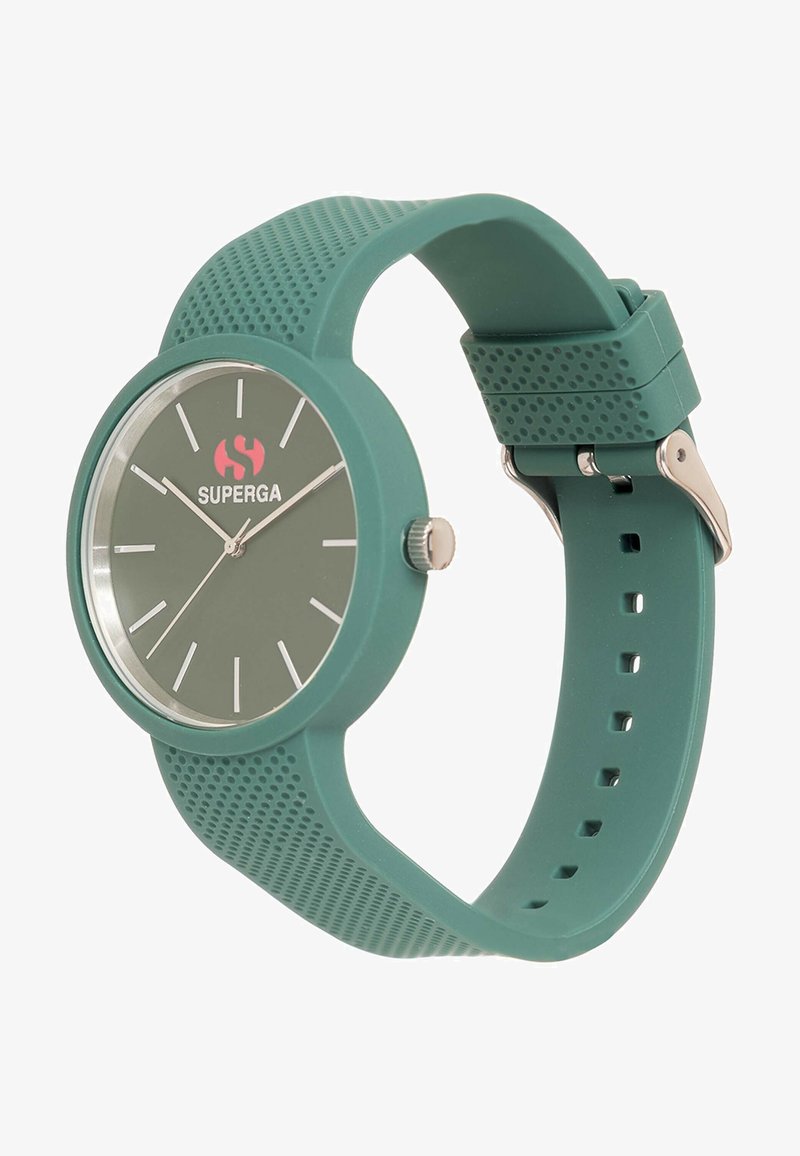 Roheline silikoonist kell, millel on ümmargune nägu, minimalistik disain, hõbedased tunni näidikud ja logo 12. kohal, kinnitatud metallklambriga.