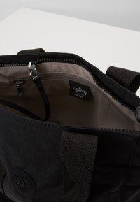 Borsa in tessuto nera con chiusura a zip, foderata internamente in marrone chiaro, include un'etichetta Kipling e una piccola tasca con zip. Manici robusti.