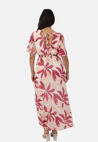 Robe maxi à dos ouvert, présentant des motifs floraux roses et pêches sur fond crème, avec des manches courtes et une taille cintrée.