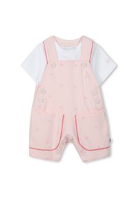 Ροζ βαμβακερή ολόσωμη φόρμα μωρού με κοντά πόδια, με διακοσμητικά κουμπιά και τσέπες, τοποθετημένη πάνω από ένα λευκό μπλουζάκι με κοντά μανίκια.