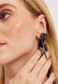 Kõrvarõngad, millel on roosi kujundus, sädelev lilla lilleke, musta vääriskivi keskus ja metallilised leheaktsendid kitseneval hõbedasel oksal.