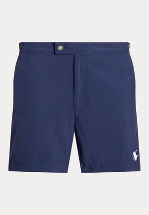 Shorts de bain bleu marine en tissu léger, avec une fermeture à boutons sur le devant, des poches latérales et un petit logo blanc sur le bas côté.