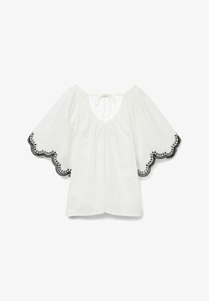 Biała bluzka z dekoltem w serek i szerokimi krótkimi rękawami. Czarna koronkowa lamówka zdobi rękawy i dół, posiadając skomplikowane faliste detale.