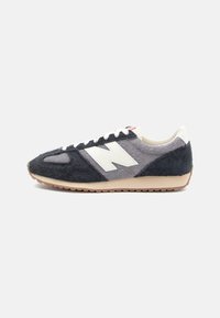 Suedesneakers med en marineblå og grå fargeskjema, med en hvit logo, snøring og såle i gummigummi. Teksturert overdel.