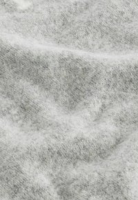 Grijs en witte textuurstof met een zachte, fuzzy uitstraling. Het materiaal vertoont een subtiel visgraatpatroon en lichte kleurvariaties.