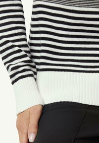 Gestickter Pullover mit abwechselnd schwarzen und weißen horizontalen Streifen, mit einem gerippten weißen Bündchen und einer figurbetonten Passform.