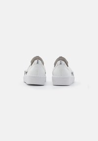Sneakers slip-on in pelle bianca con suola piatta in gomma e dettagli metallici sul tallone. I dettagli testurizzati sulla suola offrono aderenza.
