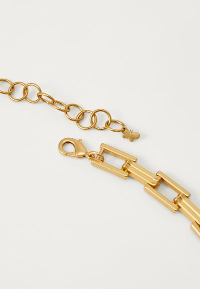Gold metal chain with circular links and rectangular accents. Features a lobster clasp and a small pendant detail. Smooth, reflective surface.