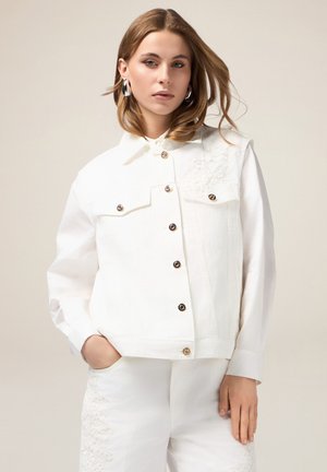 Giacca in denim bianco con colletto a punta, chiusura frontale con bottoni, due tasche sul petto e ricamo floreale sulla spalla sinistra.