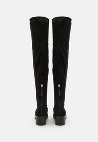 Black over-the-knee boots with a soft suede finish, fitted shape, and a chunky heel. Features visible zippers at the back.