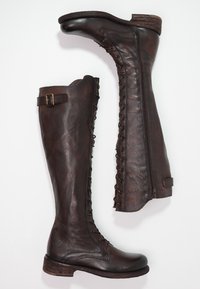 Botas de cuero marrón hasta la rodilla con punta redonda, detalles de cordones a lo largo del costado y un pequeño hebilla decorativa cerca de la parte superior.