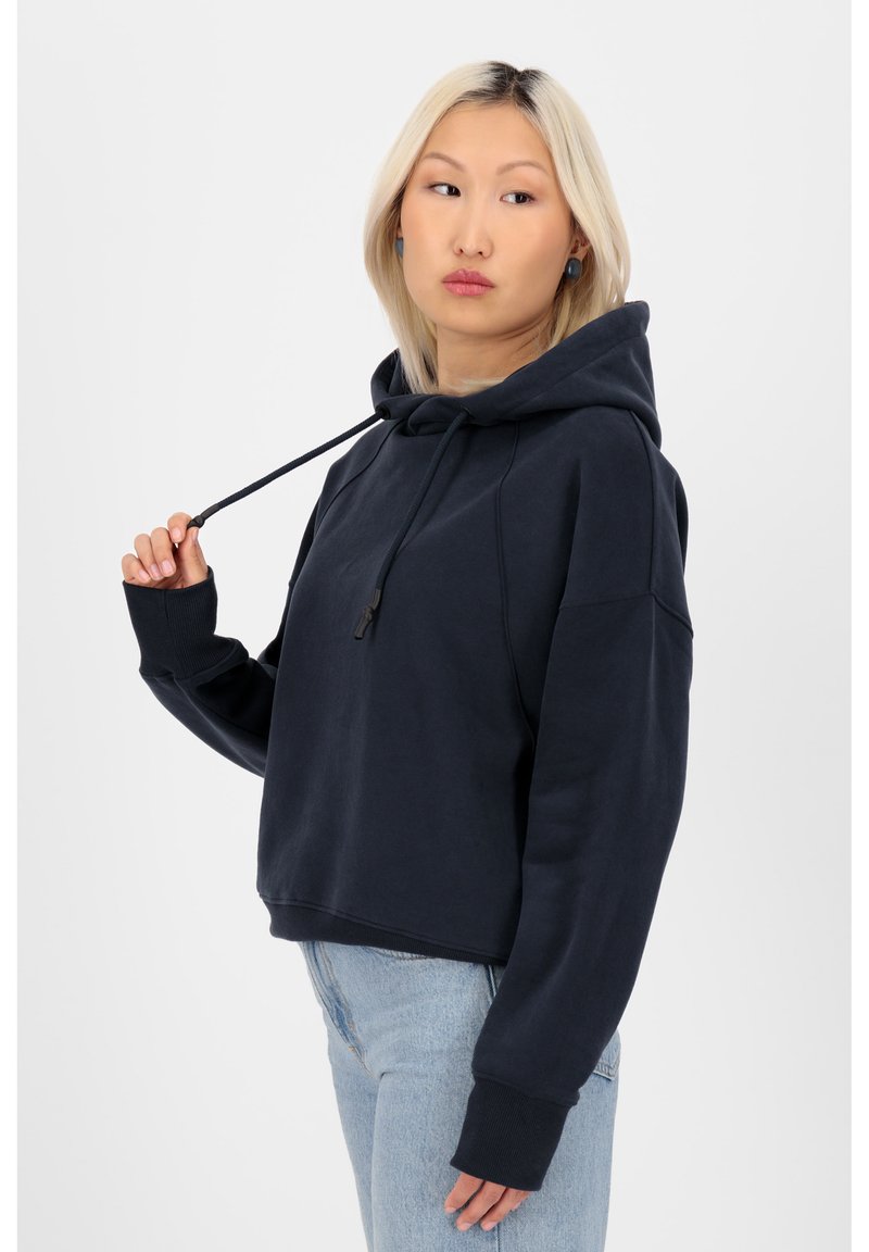 Felpa a maniche raglan cropped di colore blu navy con coulisse, senza dettagli frontali. Materiale morbido, abbinata a jeans chiari.