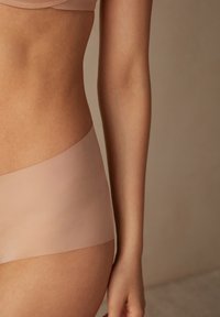Hellbraune, nahtlose, hochgeschnittene Unterwäsche aus weichem Stoff, mit glatter Textur und minimalistischem Design.