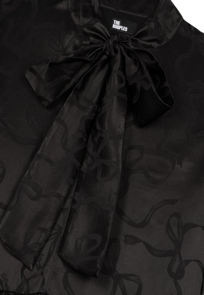Schwarze Satinbluse mit einer großen Schleife am Kragen, einem subtilen Muster aus verschlungenen Linien und einer glatten Textur.