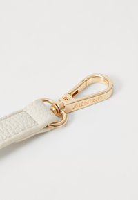 Bracelet en cuir blanc avec surface texturée, présentant un clip en métal doré portant l'inscription gravée "Valentino". Attache en forme d'anneau en métal circulaire.