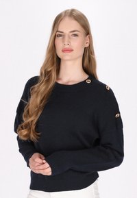 Pulover tricotat bleu marin, cu gât rotund, având nasturi aurii pe umeri și mansete cu nervuri, oferind o croială lejeră.