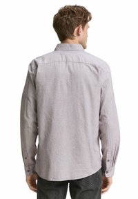 Chemise à manches longues à boutons en tissu gris clair avec un motif texturé. Présente un col et des poignets boutonnés. Vue de dos montrée.