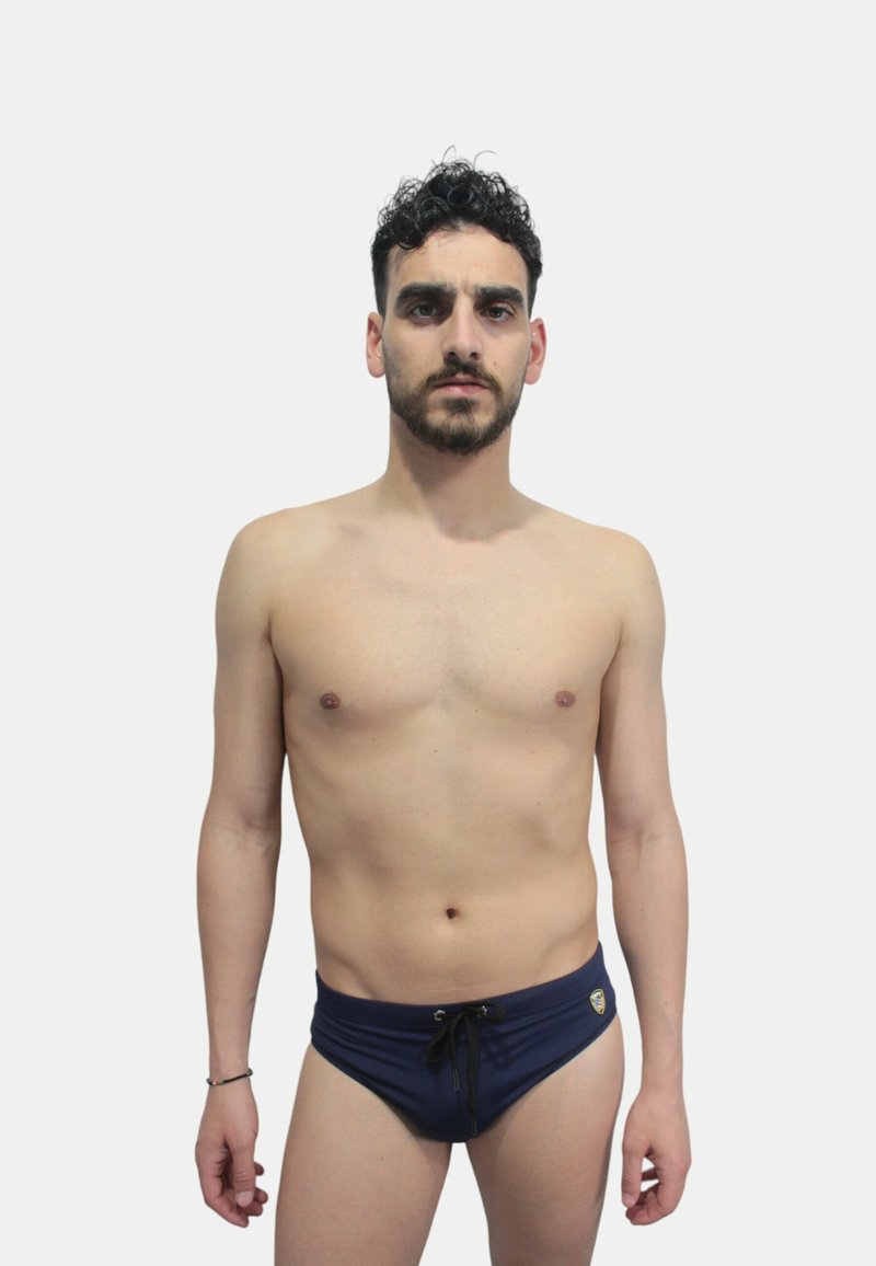 Costume da bagno slip blu navy con coulisse regolabile e dettaglio logo. Realizzato in materiale liscio, design aderente, stile minimalista.