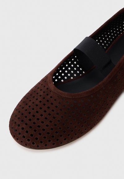 Balerini din suede perforat maro, cu vârful rotund și o curea elastică neagră peste glezna piciorului. Suprafață texturată cu interior neted.