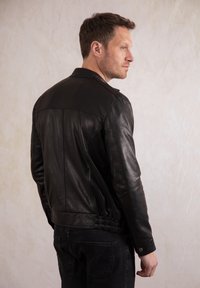 Black leather jacket with a fitted design, shoulder seams, and elasticated waist. Features a classic collar and smooth texture.