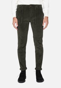 Pantaloni in velluto a coste di colore verde scuro, con vita elasticizzata e coulisse, tasche frontali e vestibilità slim. Orli arrotolati e tessuto testurizzato.