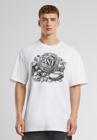 White cotton t-shirt featuring a black graphic print with decorative elements and the word "KANT" centered on the chest.