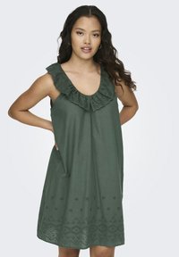 Tamnozelena haljina bez rukava s volančićem na izrezu i čipkastim obrubom na rubu, koja sadrži cvjetne izreza i slobodan kroj.