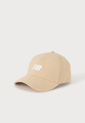 Casquette de baseball beige avec une visière incurvée et un logo New Balance brodé en blanc à l'avant.