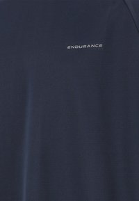 Navy urheilu paita, joka on valmistettu teksturoidusta kankaasta ja jossa on sana "ENDURANCE" valkoisena edessä. Lyhyet hihat ja pyöreä kaula-aukko.